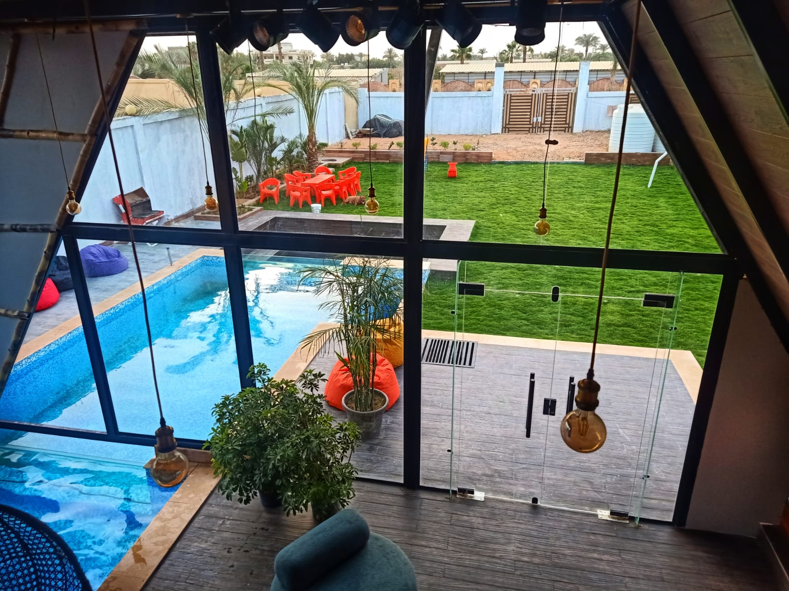 Panoramic view from inside A-frame cabin overlooking pool and garden