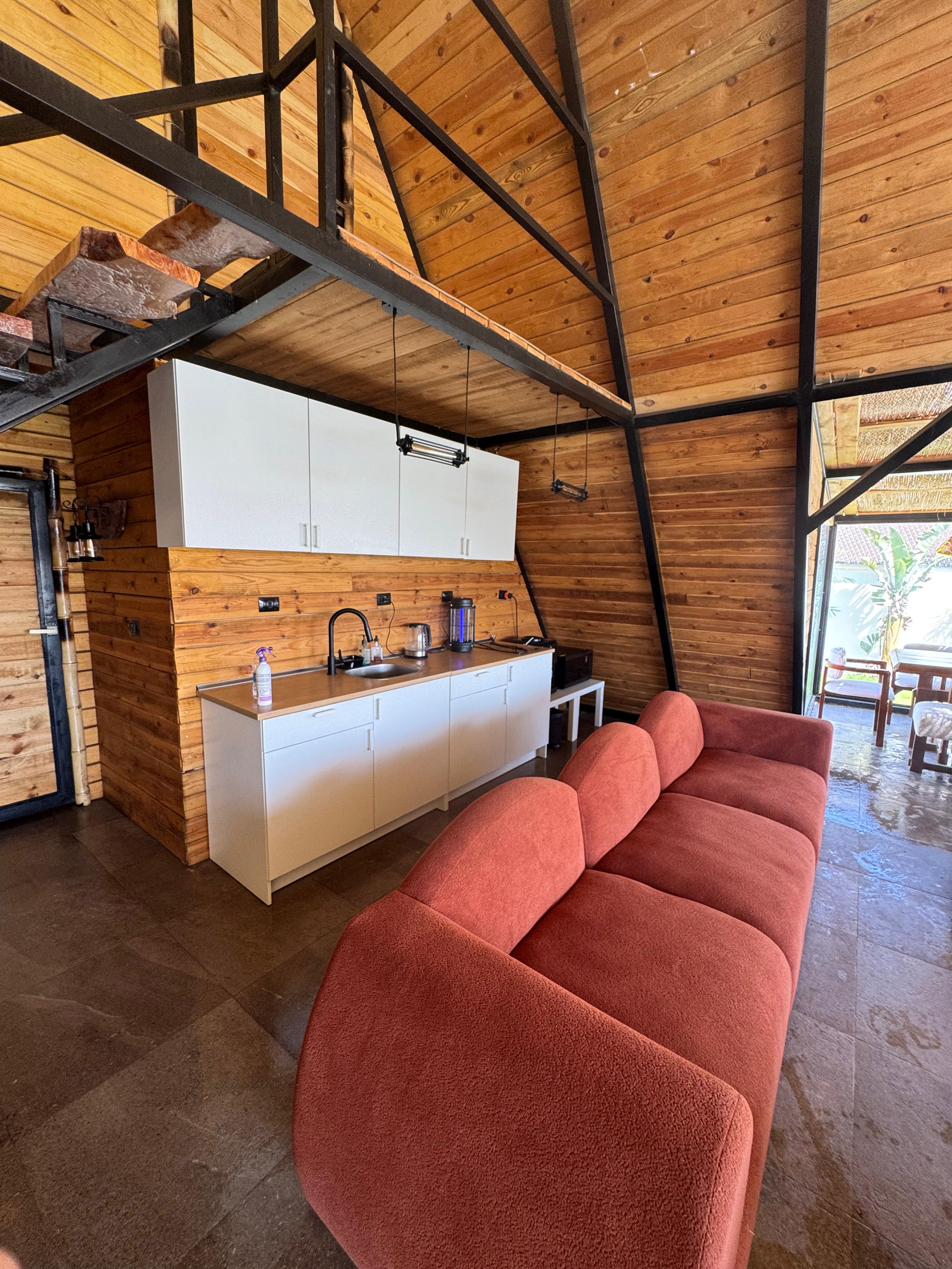 Kitchenette with white cabinets and wooden A-frame ceiling