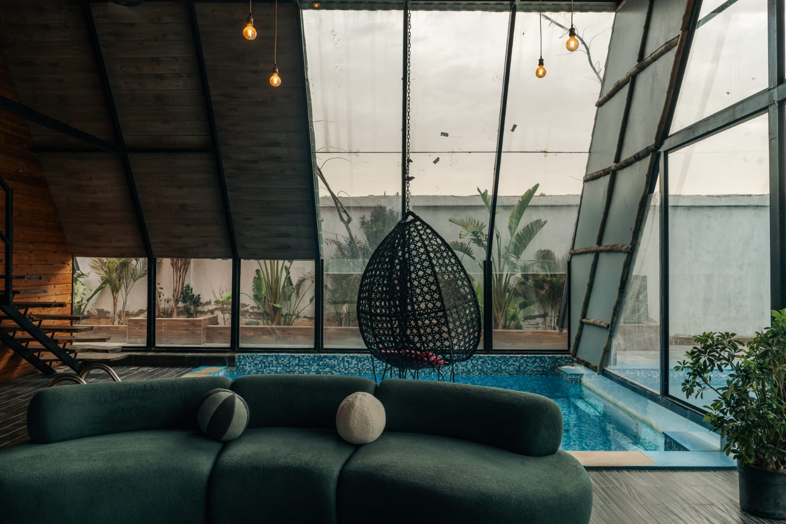 Moody living area with curved sofa and indoor pool behind glass